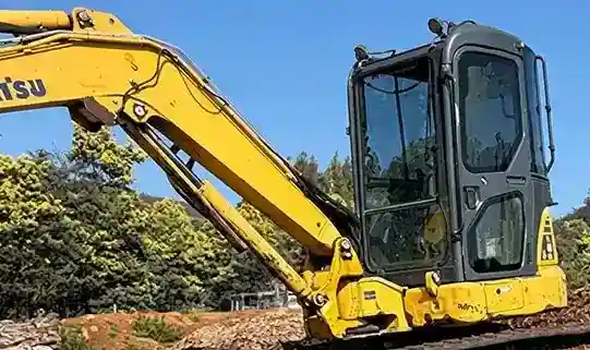Excavator clearing tree roots and stumps from a site